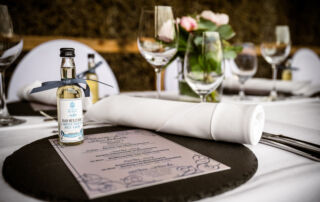 Gedeck an Gästetafel mit Platzteller, Speisekarte und Gastgeschenk (Sole-Tagetes-Likör)